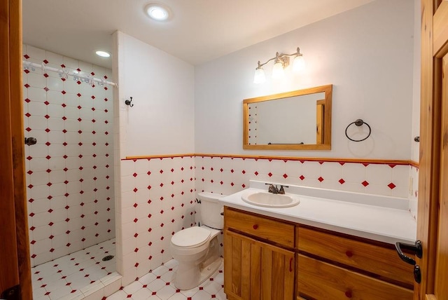 full bath with a shower stall, toilet, vanity, wainscoting, and tile walls