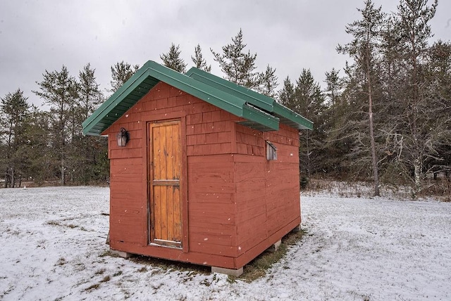 snow covered structure featuring an outbuilding and a storage unit