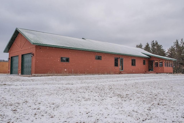 view of snow covered exterior featuring metal roof and a detached garage