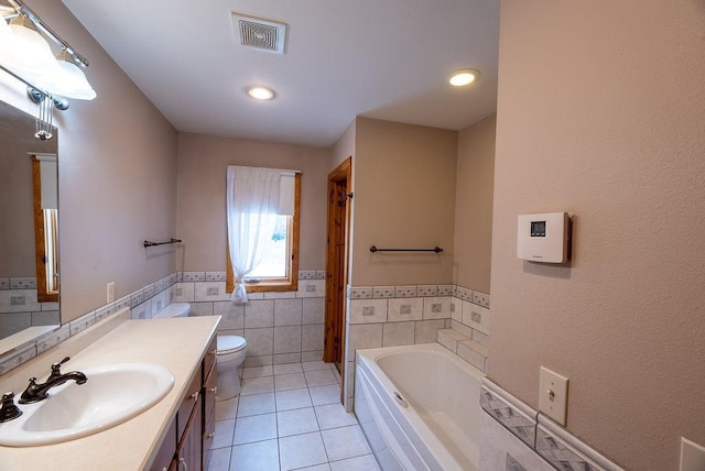 full bathroom featuring visible vents, tile walls, tile patterned flooring, a bath, and vanity