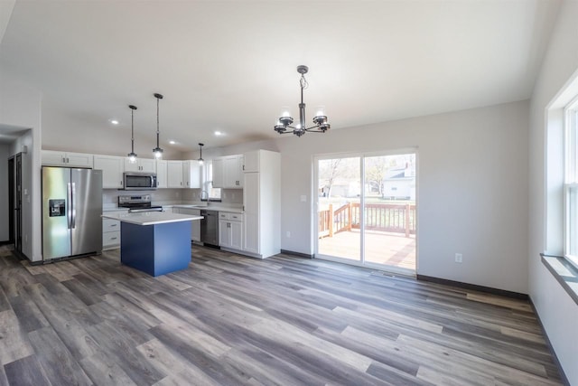 kitchen featuring a sink, wood finished floors, a center island, white cabinetry, and stainless steel appliances