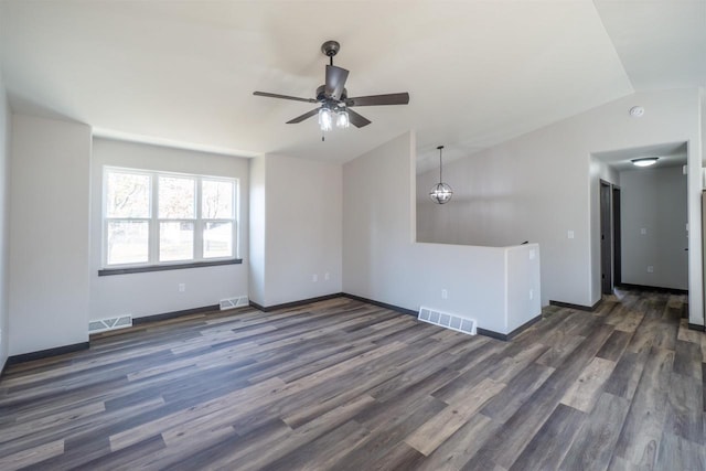 spare room with visible vents, lofted ceiling, baseboards, and dark wood finished floors