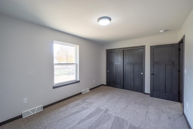 unfurnished bedroom featuring carpet flooring, baseboards, and visible vents