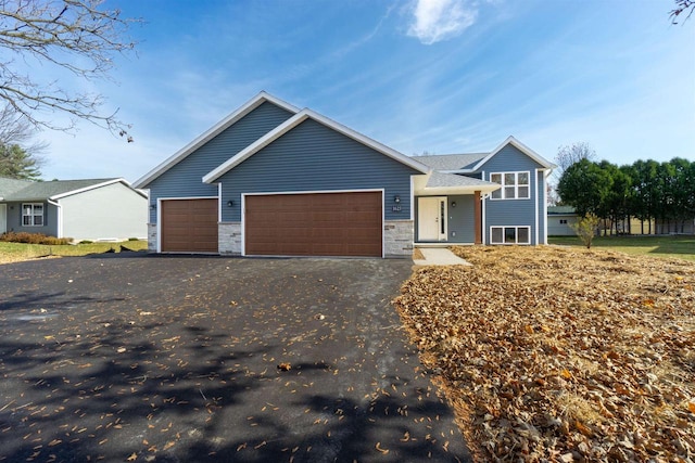 view of front of property with aphalt driveway, stone siding, and a garage