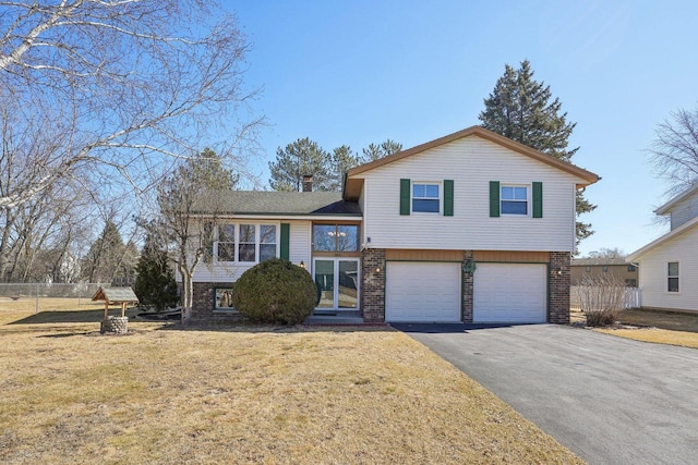 tri-level home featuring aphalt driveway, an attached garage, brick siding, and a front lawn