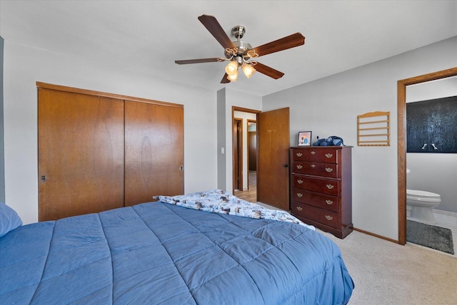 carpeted bedroom featuring a closet, baseboards, ensuite bath, and ceiling fan