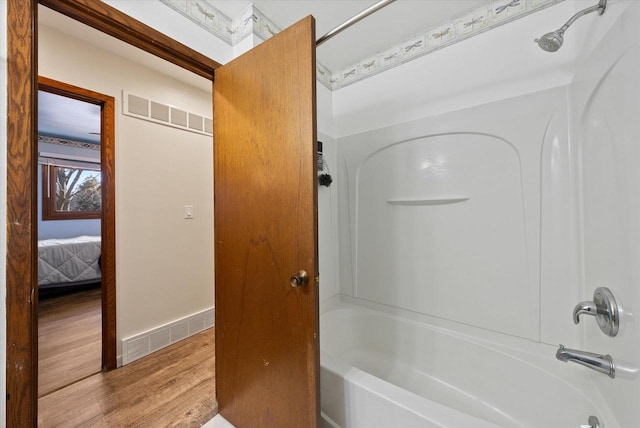 ensuite bathroom featuring visible vents, shower / tub combination, ensuite bath, and wood finished floors