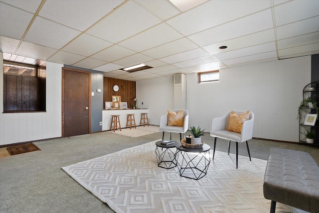 living area with a drop ceiling and carpet