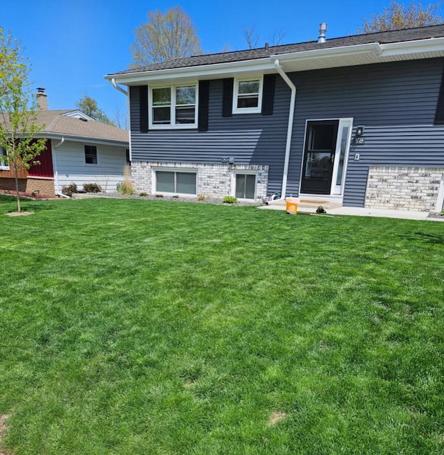 rear view of property with a lawn and brick siding