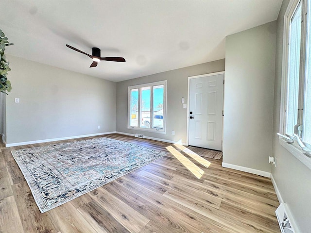 interior space with visible vents, light wood-style flooring, a ceiling fan, and baseboards