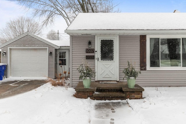 snow covered property entrance with a garage