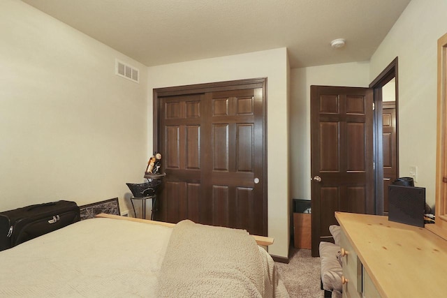 bedroom featuring light carpet, visible vents, and a closet