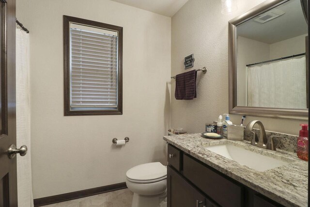 bathroom with vanity, toilet, and baseboards