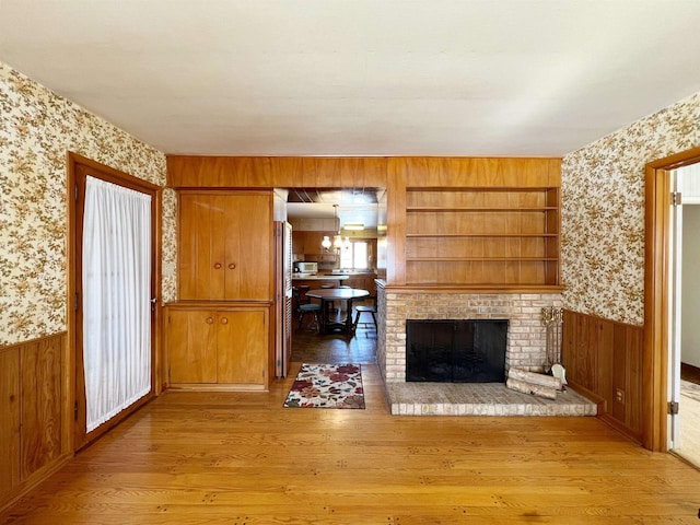 unfurnished living room featuring wallpapered walls and a wainscoted wall