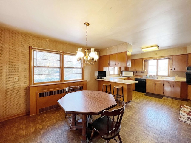 dining space featuring baseboards, a chandelier, radiator heating unit, and wallpapered walls