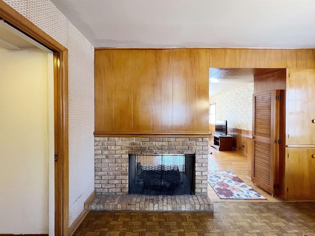 unfurnished living room with parquet flooring, wooden walls, and a fireplace