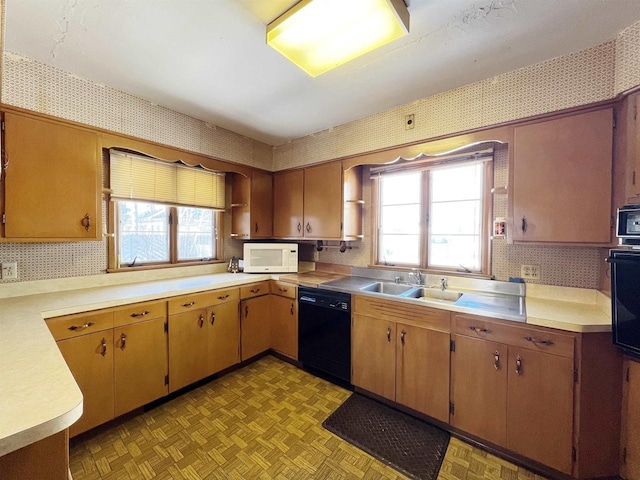 kitchen with wallpapered walls, black appliances, light countertops, and a sink