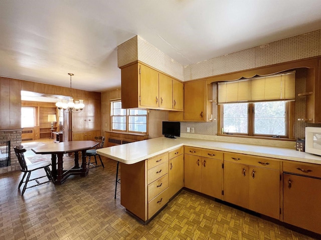 kitchen featuring white microwave, a peninsula, a fireplace, and light countertops