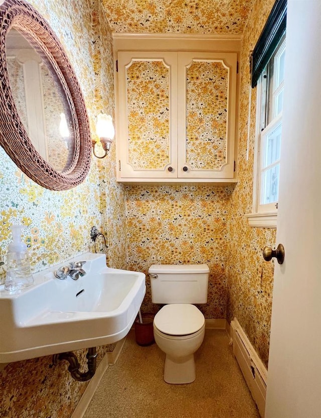 bathroom featuring wallpapered walls, a baseboard heating unit, baseboards, toilet, and a sink