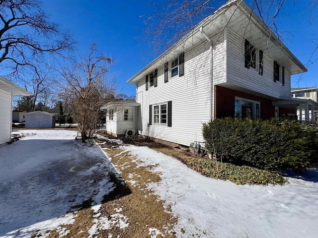 snow covered property with a storage unit and an outbuilding