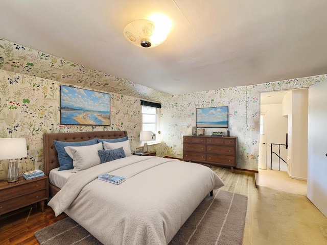 bedroom featuring wood finished floors and wallpapered walls