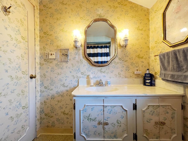 bathroom featuring baseboards, vanity, and wallpapered walls