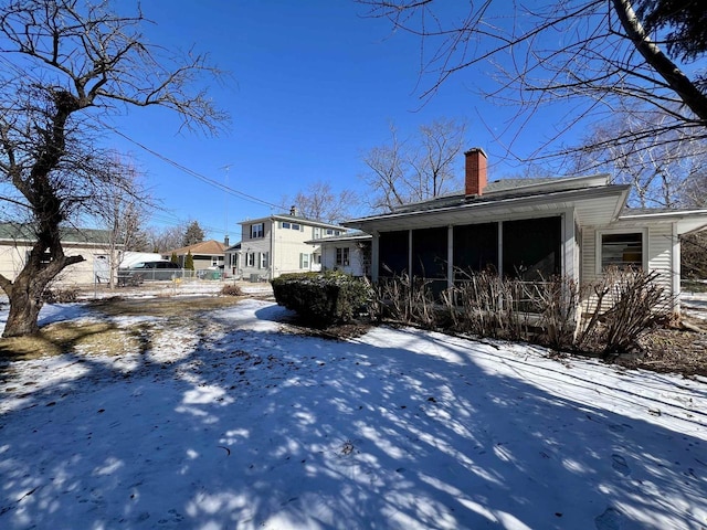 view of snow covered exterior with a sunroom and a chimney