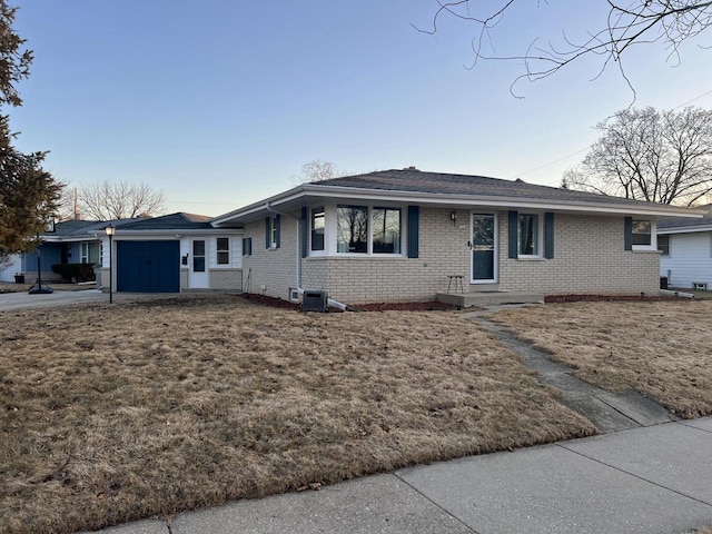 ranch-style house with driveway, brick siding, and an attached garage