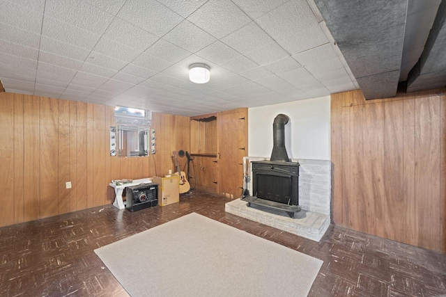 unfurnished living room with wooden walls and a wood stove