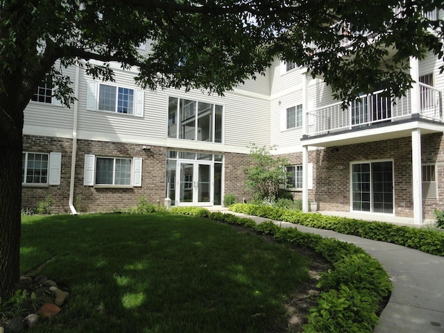 back of house with a yard and brick siding