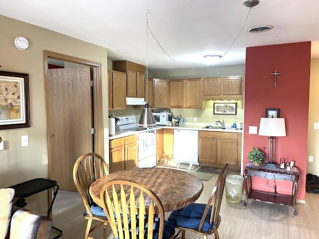 kitchen featuring white appliances, visible vents, a sink, light countertops, and under cabinet range hood