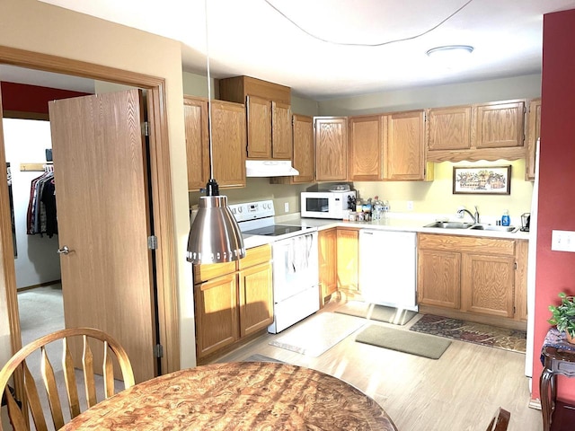 kitchen with white appliances, a sink, light countertops, light wood-style floors, and under cabinet range hood