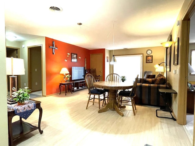 dining room featuring baseboards, visible vents, and light wood finished floors