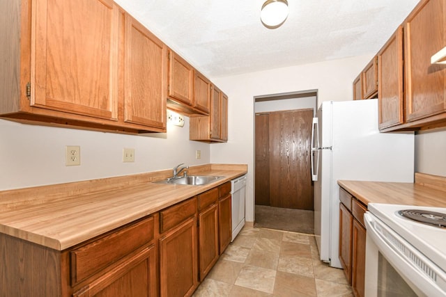 kitchen featuring a sink, white appliances, a textured ceiling, and brown cabinets