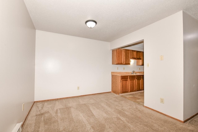 kitchen featuring brown cabinetry, light carpet, baseboards, and a baseboard radiator