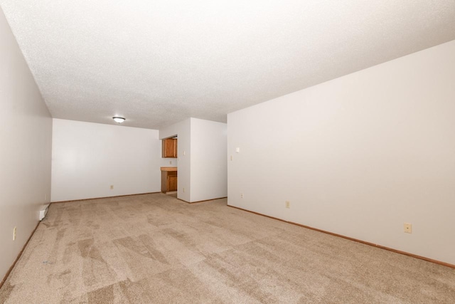 empty room with a textured ceiling and light carpet