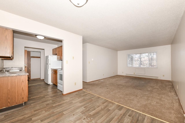 unfurnished living room with baseboards, a baseboard radiator, wood finished floors, a textured ceiling, and a sink