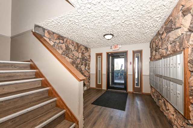 foyer featuring mail area, wood finished floors, and stairway