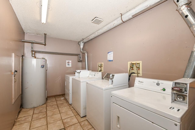 washroom featuring gas water heater, separate washer and dryer, a textured ceiling, and light tile patterned floors