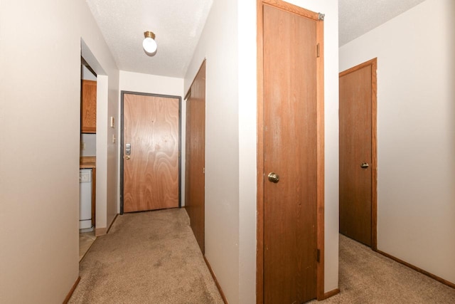 hall featuring light carpet, a textured ceiling, and baseboards