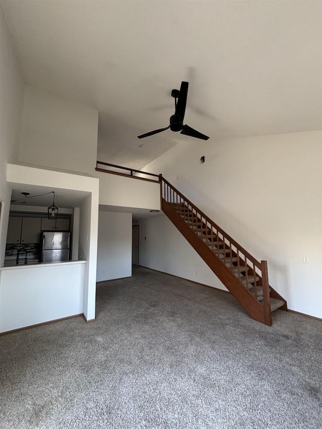 unfurnished living room with stairway, baseboards, lofted ceiling, and ceiling fan