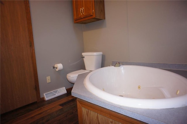 full bathroom with visible vents, toilet, a jetted tub, and wood finished floors