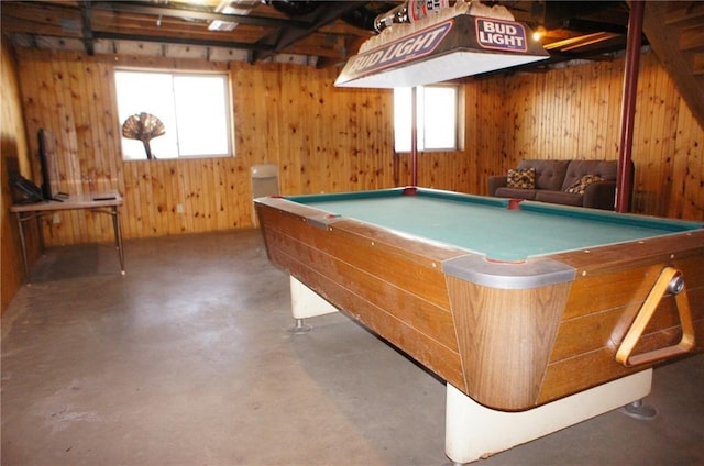 recreation room with wooden walls, a healthy amount of sunlight, concrete flooring, and billiards