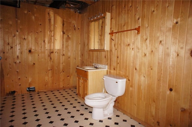 bathroom featuring vanity, tile patterned floors, toilet, and wood walls