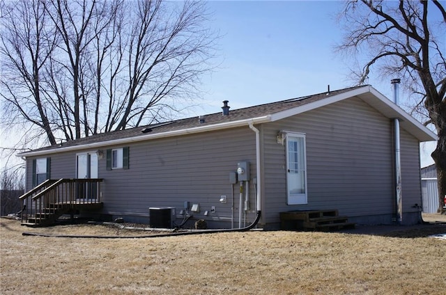 rear view of property featuring a lawn and central AC