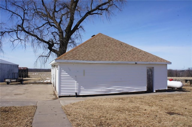 view of property exterior featuring an outbuilding and roof with shingles