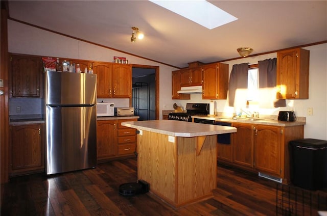 kitchen featuring dark wood-style flooring, stainless steel appliances, light countertops, under cabinet range hood, and lofted ceiling with skylight