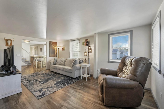 living area with a healthy amount of sunlight, wood finished floors, and stairs