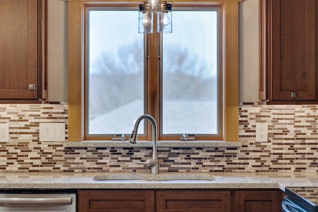 kitchen with a sink, decorative backsplash, and stainless steel dishwasher