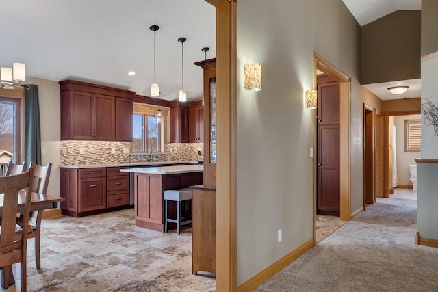 kitchen with a kitchen bar, backsplash, light countertops, baseboards, and vaulted ceiling